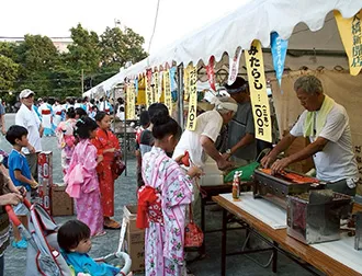 地域貢献(盆踊り大会、浴衣を着て出店で買いものをする女の子)